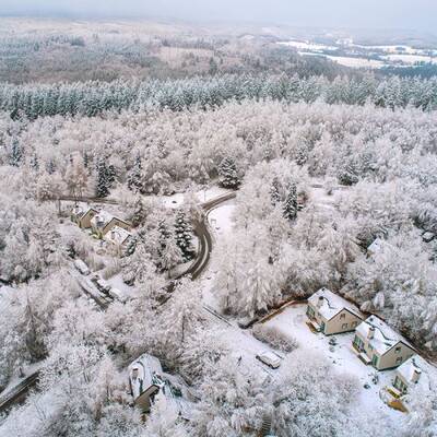 Winterluftaufnahme von Center Parcs Les Ardennes mit einigen Ferienhäusern zwischen den Bäumen