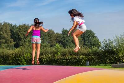 Kinder springen auf dem Lufttrampolin auf dem Spielplatz im Ferienpark EuroParcs Zuiderzee