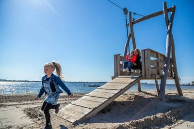 Kinder auf einem Spielplatz am Strand des Veluwemeeres im Ferienpark EuroParcs Zuiderzee