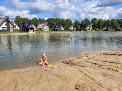 Mädchen spielt am Strand eines Ferienhauses am Wasser bei Landal Drentse Lagune