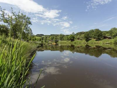 Erholungsteich im Ferienpark Landal Wirfttal mit Ferienhäusern im Hintergrund