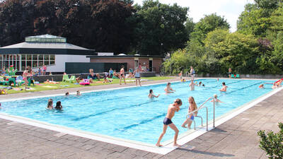 Menschen schwimmen im Außenpool des Ferienparks Molecaten Park Landgoed Ginkelduin