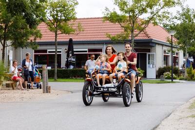 Menschen auf einem großen Familienfahrrad im Ferienpark RCN Toppershoedje