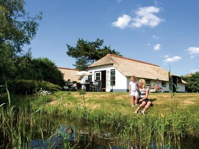 Menschen am Wasser in ihrem Ferienhaus im Ferienpark Roompot De Veluwse Hoevegaerde