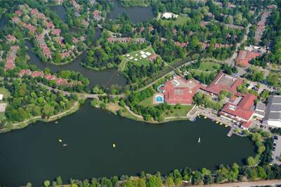 Luftaufnahme von Ferienhäusern und dem Freizeitsee des Roompot Vakantiepark Weerterbergen