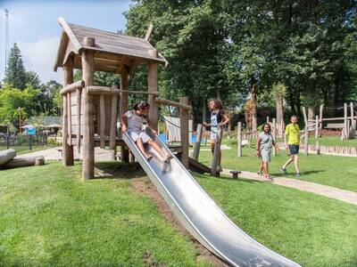 Kind rutscht die Rutsche auf einem Spielplatz im Ferienpark Topparken Landgoed de Scheleberg