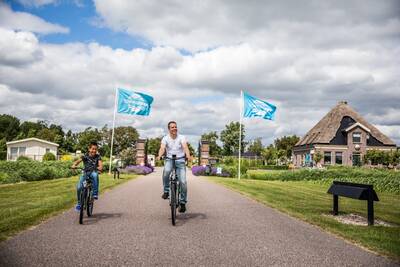 Menschen radeln am Eingang des Ferienparks Topparken Park Westerkogge