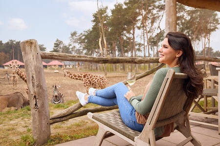 Eine Frau blickt von der Terrasse einer Lodge im Safari Resort Beekse Bergen über die Savanne