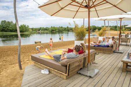 Menschen auf Liegestühlen auf der Terrasse der Beachbar im Ferienpark BreeBronne