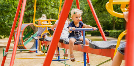 Kinder auf der Familienschaukel auf einem Spielplatz im Ferienpark BreeBronne