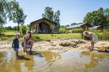 Kinder spielen im Wasser des Sees in den Safarizelten von Camping Vreehorst