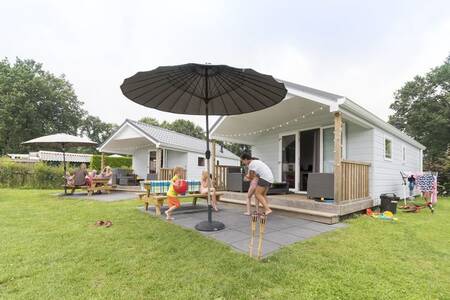 Familie im Garten einer Lodge im Ferienpark Camping de Noetselerberg