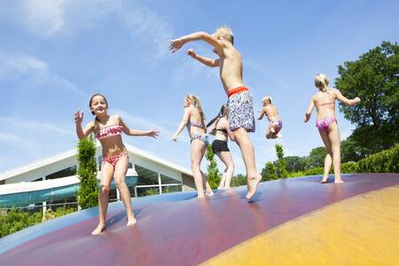 Kinder springen auf dem Lufttrampolin auf einem Spielplatz im Ferienpark Camping de Noetselerberg