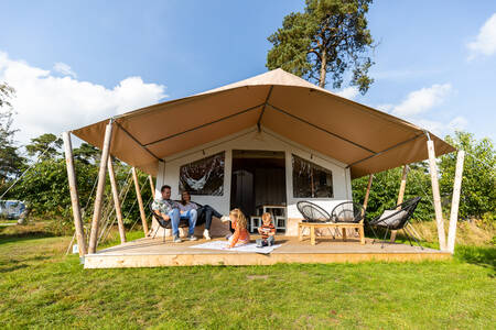 Menschen unter dem Vordach eines Safarizeltes im Ferienpark Camping de Norgerberg