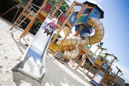 Kind rutscht die Rutsche auf einem Spielplatz im Ferienpark De Boshoek hinunter