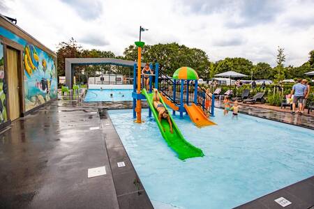 Kinder auf Spielgeräten im überdachten Freibad von De Witte Berg