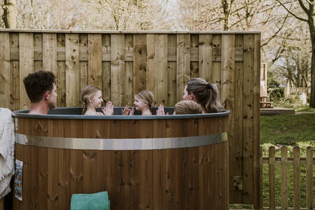 Eine Familie sitzt im Whirlpool im Garten eines Bungalows im Ferienpark Dierenbos