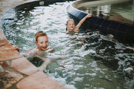 Kinder schwimmen in den Stromschnellen des Hallenbades im Ferienpark Dierenbos