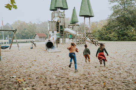 Kinder rennen zu einem großen Klettergerüst auf einem Spielplatz im Ferienpark Dierenbos