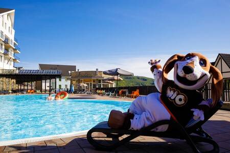 Maskottchen Mio auf einer Liege am Freibad des Ferienparks Dormio Eifeler Tor