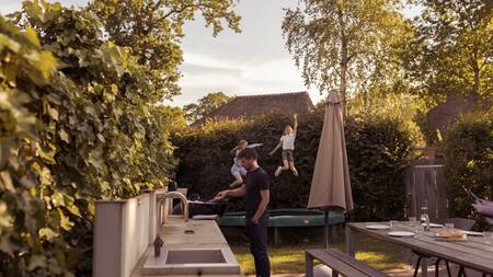 Kinder springen auf einem Trampolin im Garten einer Villa im Ferienpark Dutchen Park Duynvoet