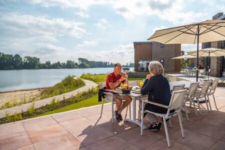 Paar im Garten eines Ferienhauses am Wasser im Ferienpark EuroParcs Aan de Maas