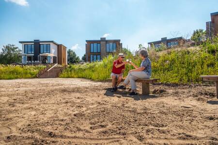 Ein Paar sitzt auf einer Bank am Strand des Ferienparks EuroParcs Aan de Maas