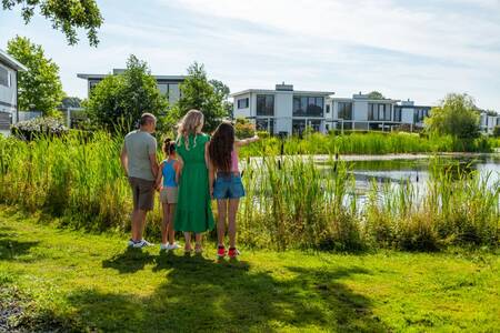 Die Familie blickt über das Wasser auf die Ferienhäuser im Ferienpark EuroParcs Bad Hulckesteijn