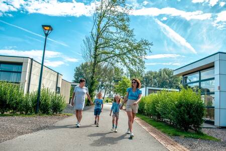 Die Familie geht zwischen den Ferienhäusern im Ferienpark EuroParcs Bad Hulckesteijn spazieren