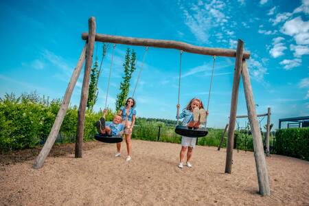 Kinder auf der Schaukel auf einem Spielplatz im Ferienpark EuroParcs Bad Hulckesteijn
