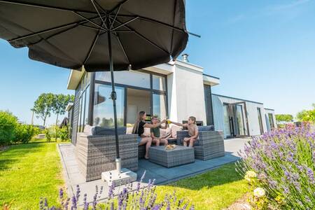 Eine Familie auf einer Lounge im Garten eines Ferienhauses im Ferienpark EuroParcs Bad MeerSee