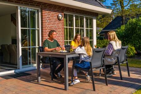 Familie am Tisch im Garten eines Ferienhauses im Ferienpark EuroParcs Beekbergen