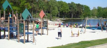 Kinder spielen auf dem Spielplatz neben dem See im Ferienpark EuroParcs Brunssummerheide