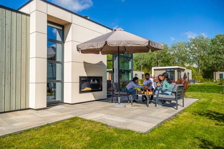 Familie am Tisch im Garten eines Ferienhauses im Ferienpark EuroParcs Buitenhuizen