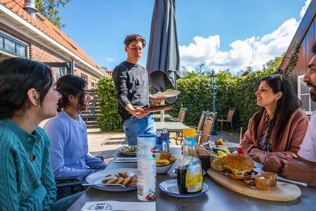 Familie isst auf der Terrasse des Restaurants im Ferienpark EuroParcs Buitenhuizen