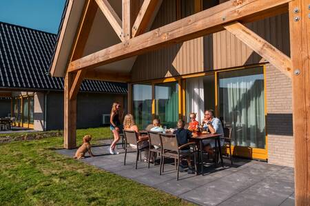 Familie sitzt auf der Terrasse eines freistehenden Ferienhauses im Ferienpark EuroParcs Cadzand