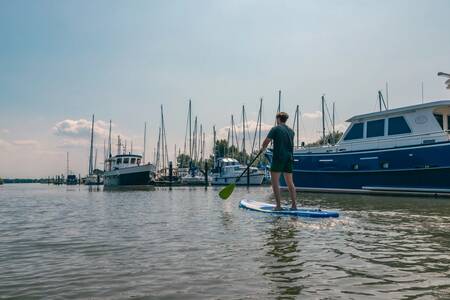 Mann auf einem Supboard im Jachthafen des Ferienparks EuroParcs De Biesbosch