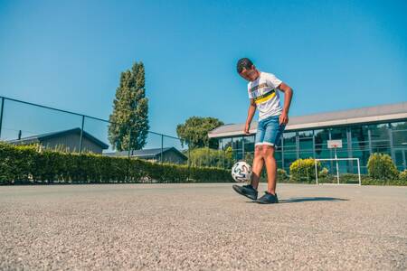 Junge spielt Fußball auf dem Spielfeld des Ferienparks EuroParcs De Biesbosch