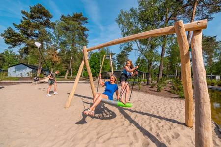 Kinder spielen auf der Schaukel auf einem Spielplatz im Ferienpark EuroParcs De Hooge Veluwe