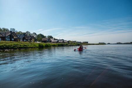 Menschen, die im Ferienpark EuroParcs De IJssel Eilanden an den Ferienhäusern vorbeifahren