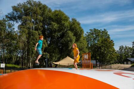 Kinder auf einem Lufttrampolin auf dem Spielplatz im Ferienpark EuroParcs De IJssel Eilanden