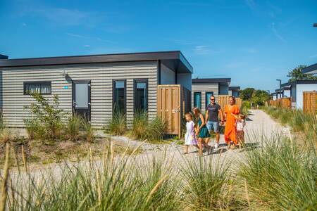 Familienspaziergänge auf einem Pfad vorbei an Chalets im Ferienpark EuroParcs De Koog