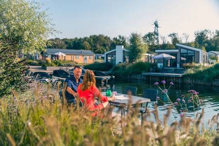 Ein Paar auf einem Steg eines Ferienhauses im Ferienpark EuroParcs De Kraaijenbergse Plassen