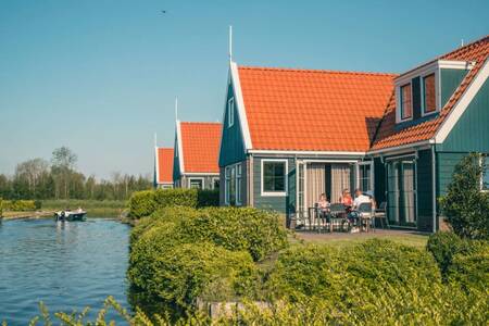 Menschen im Garten eines freistehenden Ferienhauses am Wasser im Ferienpark EuroParcs De Rijp