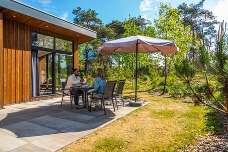 Paar an einem Tisch im Garten eines Ferienhauses im Ferienpark EuroParcs De Wije Werelt