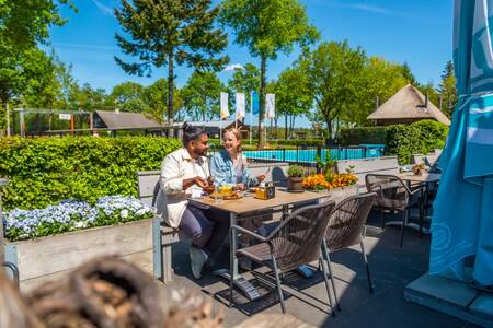Paar isst auf der Terrasse des Restaurants im Ferienpark EuroParcs De Wije Werelt