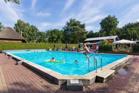 Menschen schwimmen im Außenpool des Ferienparks EuroParcs De Wije Werelt