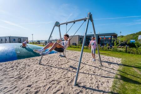 Kind auf der Schaukel auf dem Spielplatz im Ferienpark EuroParcs Enkhuizer Strand