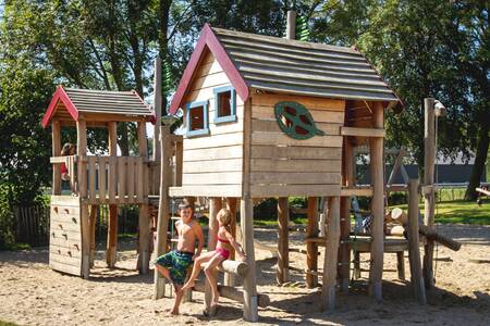 Zwei Kinder an hölzernen Spielgeräten auf dem Spielplatz des Ferienparks EuroParcs Gulperberg