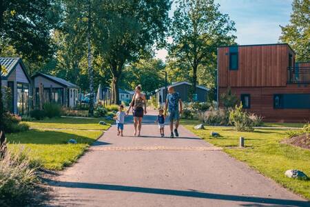 Die Familie geht zwischen den Ferienhäusern im Ferienpark EuroParcs Kaatsheuvel spazieren